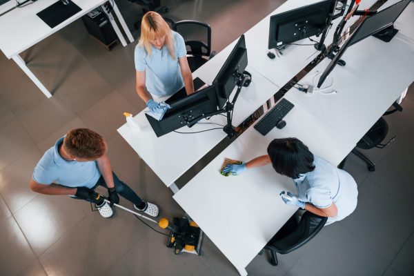 Top view. Group of workers clean modern office together at daytime.
